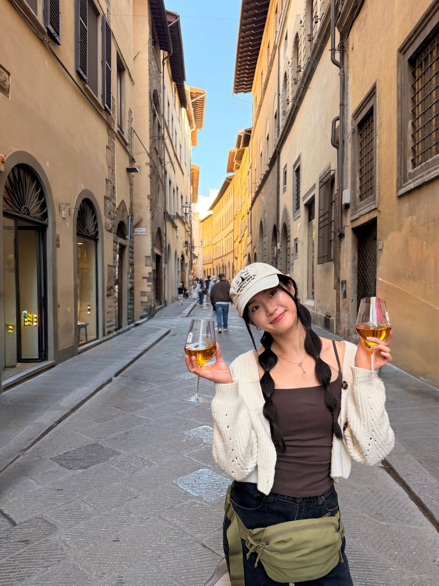Holding two glasses of orange wine on a street near Babae in Florence