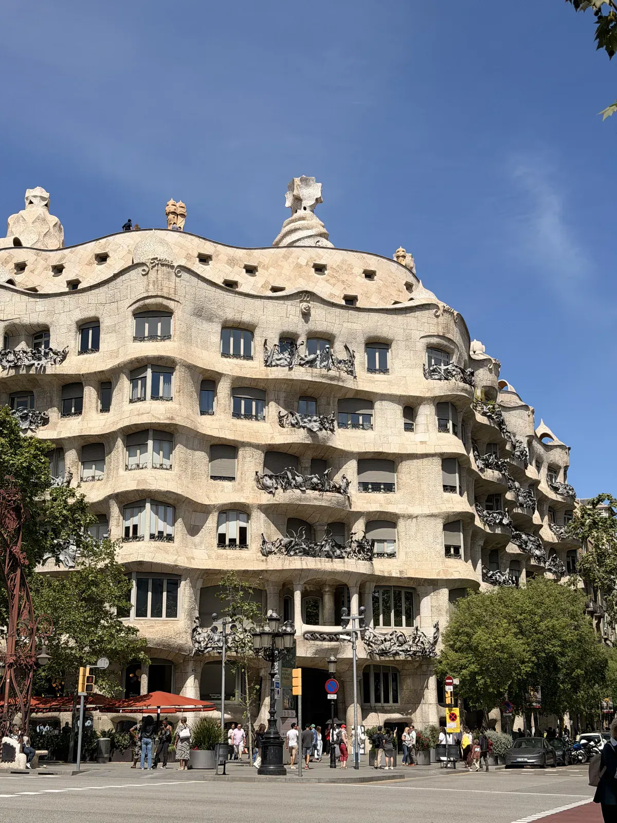 The rippling stone façade and iron balconies of Gaudí’s Casa Milà, known as La Pedrera, seen from the street corner.