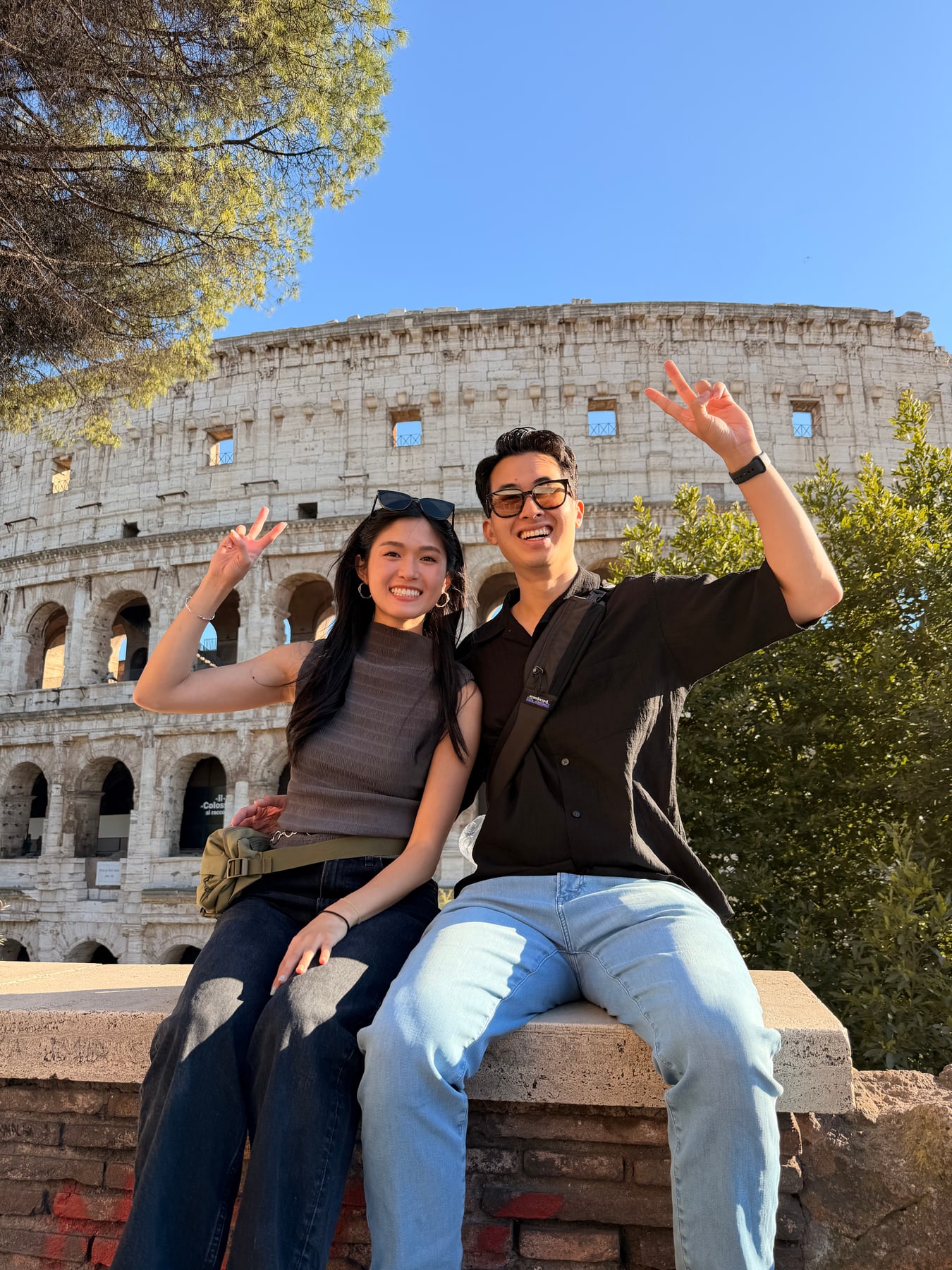 Two travelers sitting outside the Colosseum on a sunny day