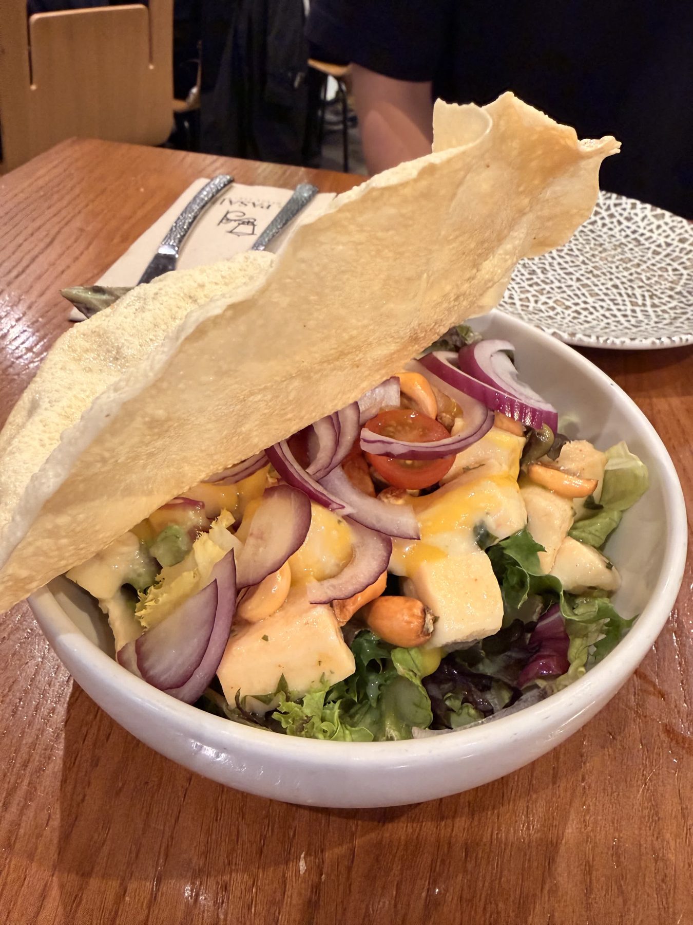 A salad bowl with cheese, onion, tomatoes, and a crisp cracker at El Pasaje in Seville