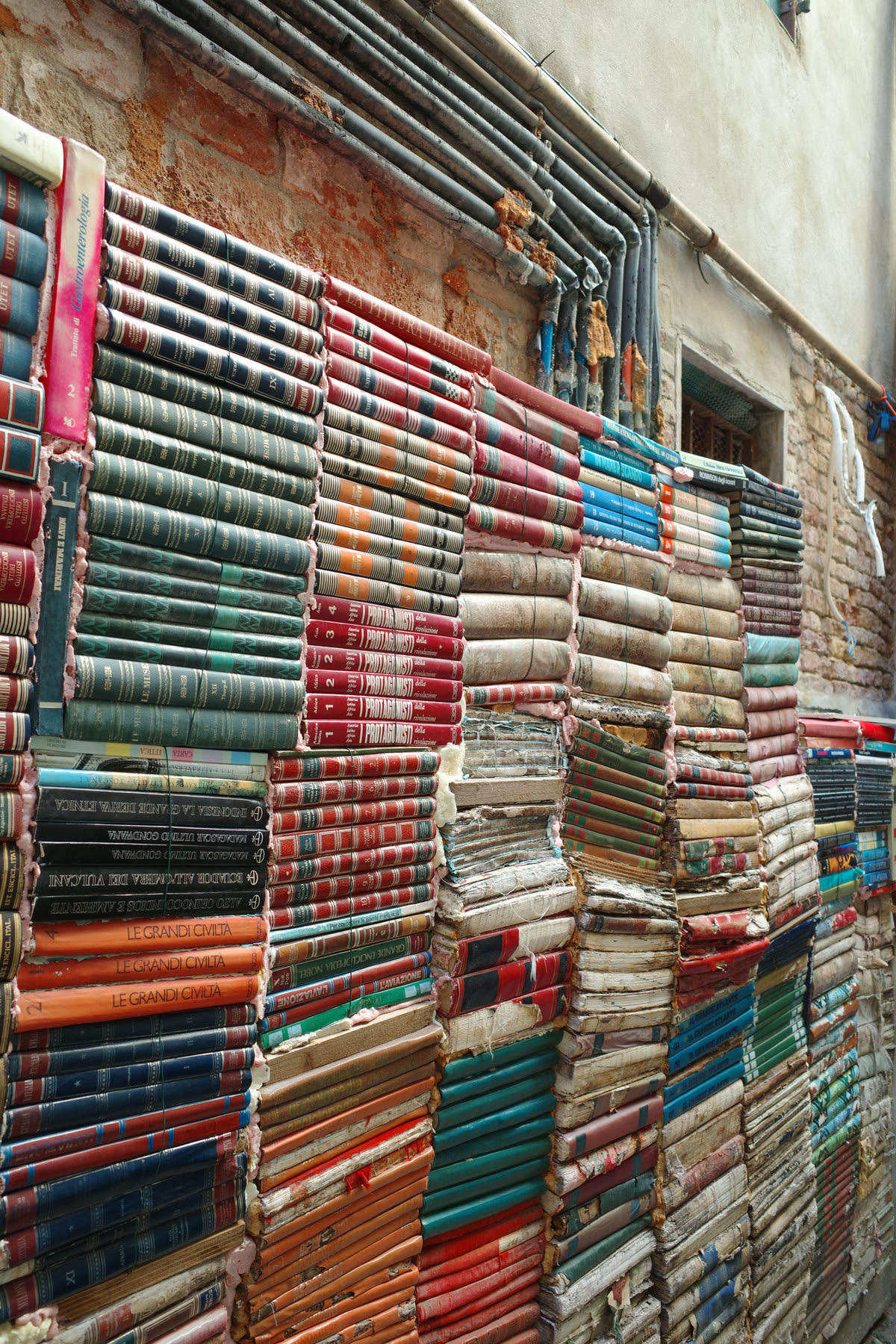 Colorful wall of weathered books at Libreria Acqua Alta in Venice