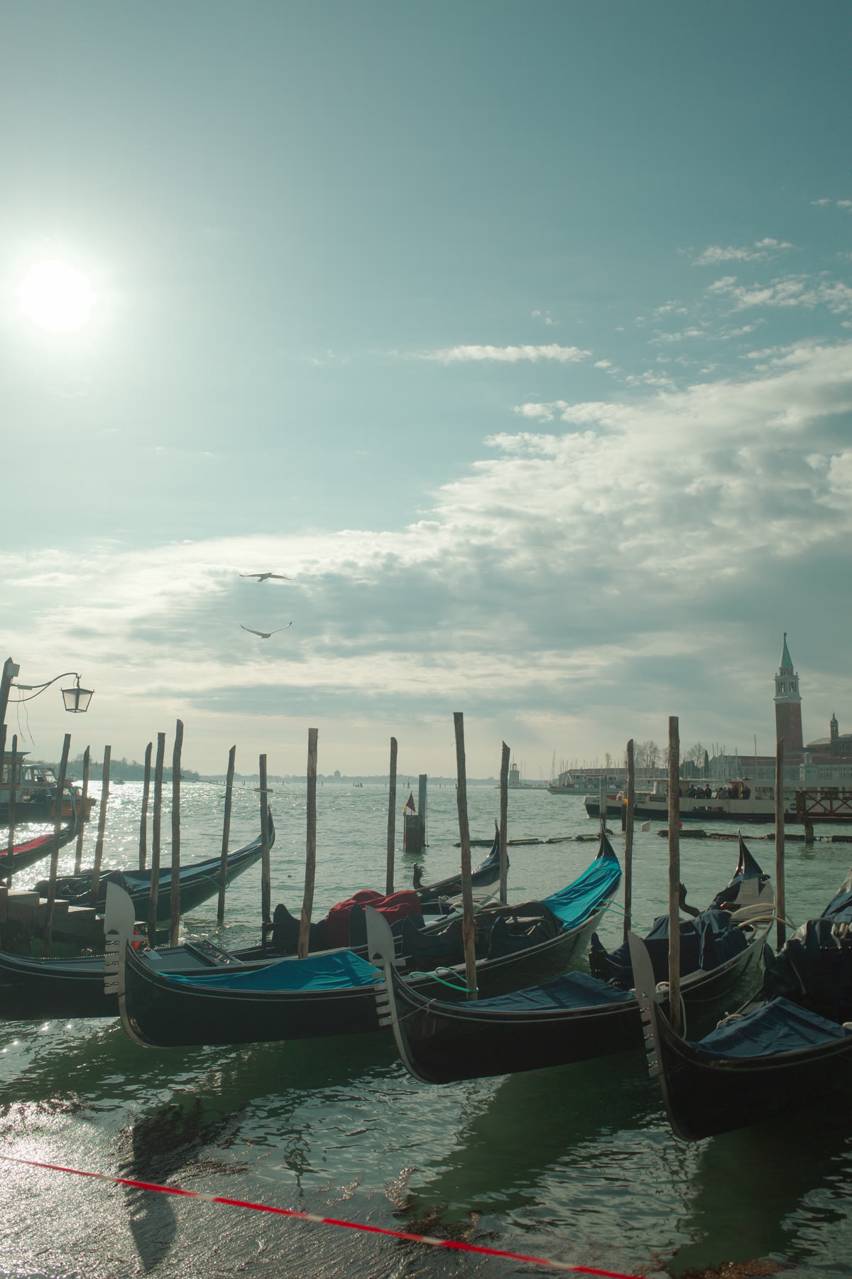 Gondolas silhouetted in hazy sunlight on the Venetian Lagoon